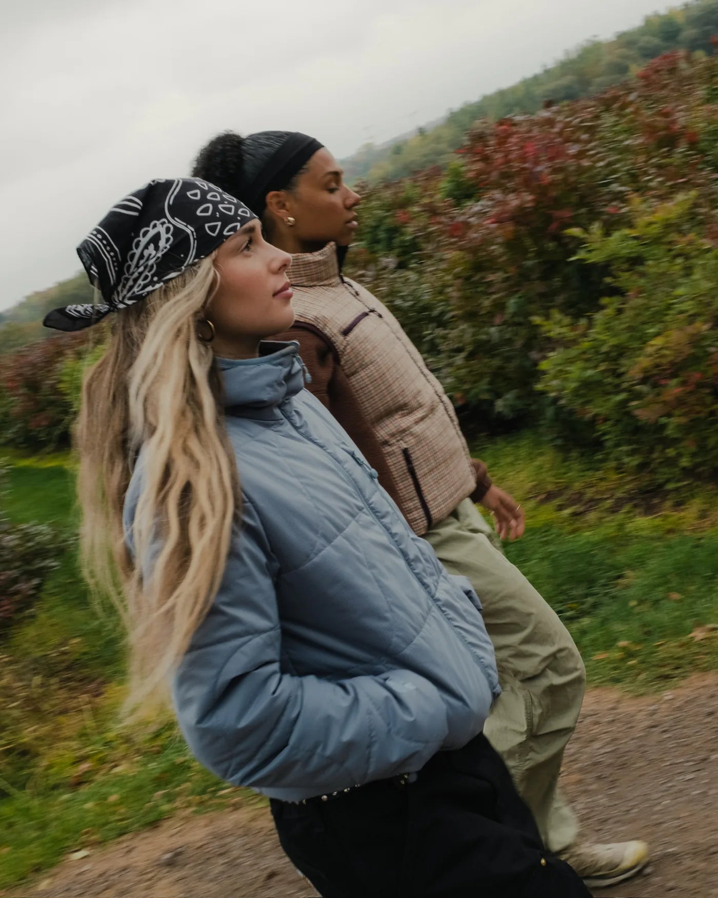 two people in a blue puffer and checked vest walking outside