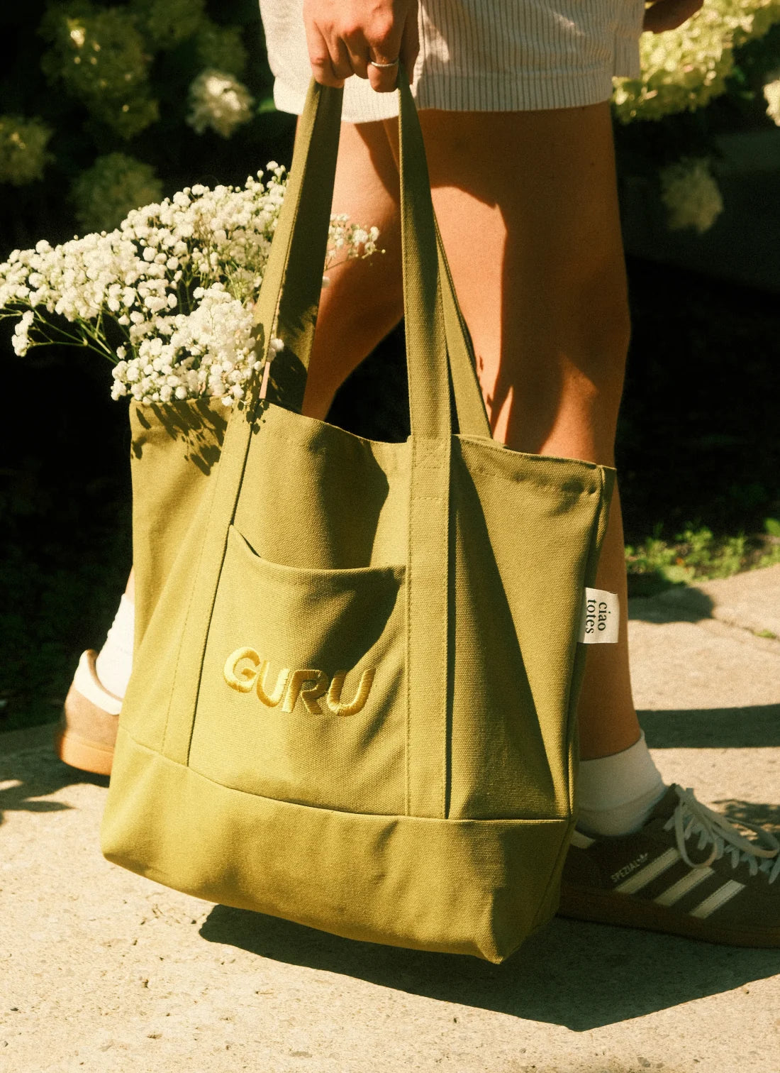 Tote bag GURU x Ciao Totes porté à l'extérieur avec bouquet de fleurs