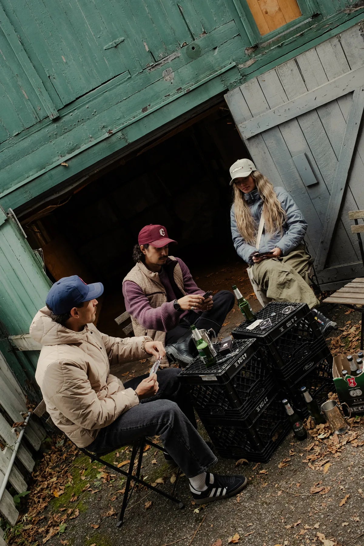 three people in ciao jackets and vests playing cards outside a barn