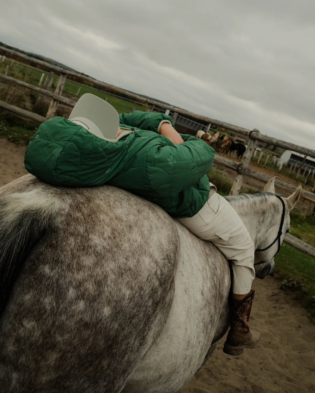 a person in a green puffer resting on a horse